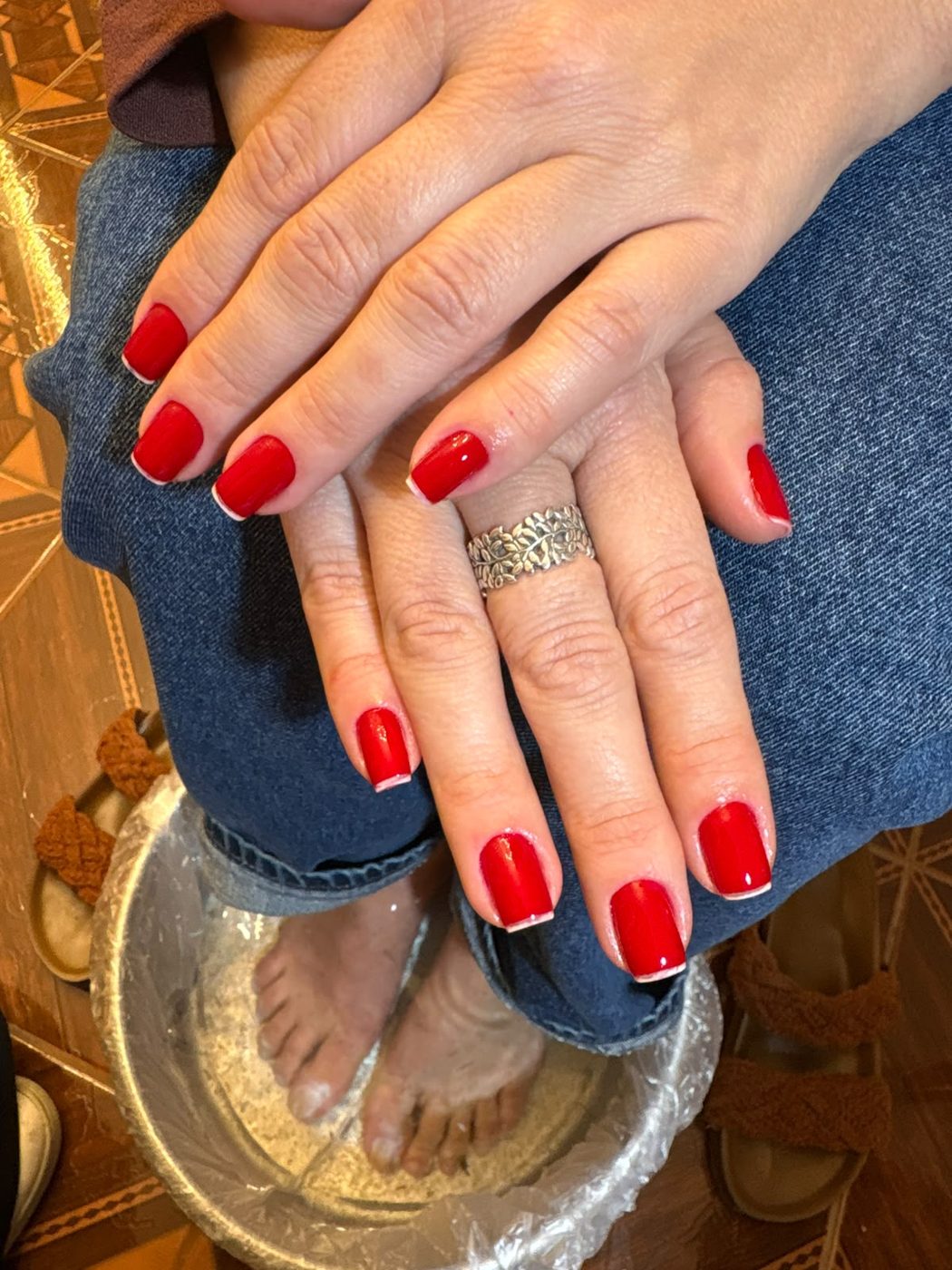 Mãos com esmalte vermelho e pés no escalda-pés